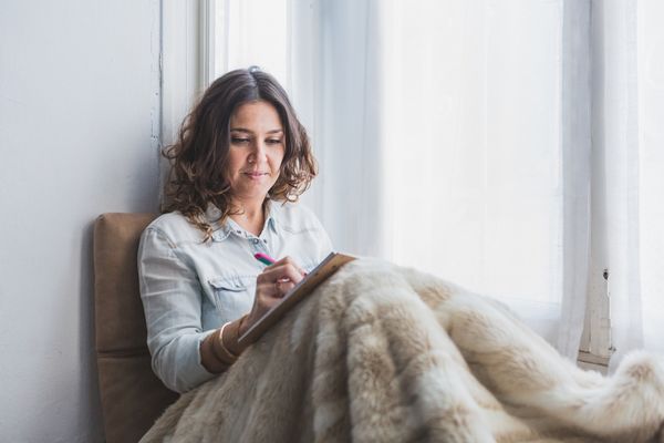 Mujer escribiendo en libreta en un momento de reflexión como parte del bienestar para mujeres en Ellas en Armonía