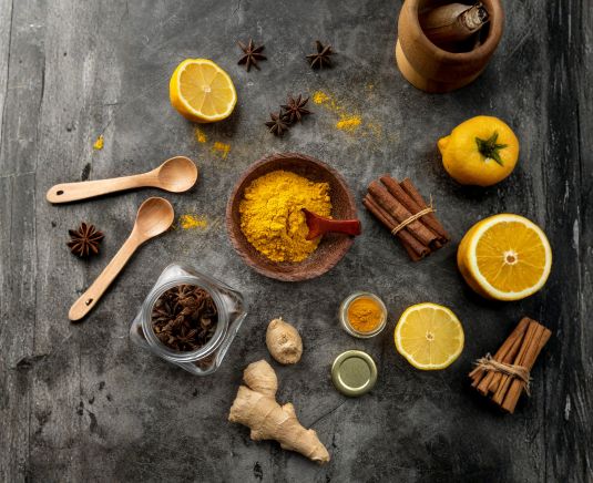 Ingredientes naturales y especias utilizadas en herbolaria para bienestar sobre una superficie oscura y artesanal