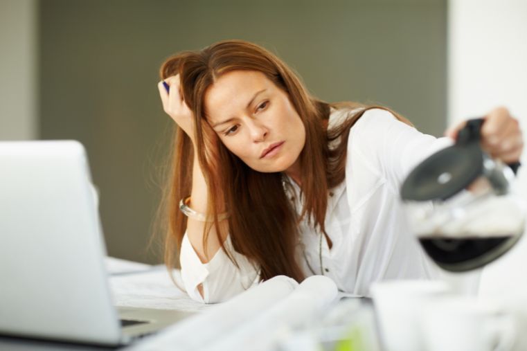 Mujer sintiéndose desgastada mientras trabaja desde casa, representando cansancio emocional y necesidad de bienestar natural